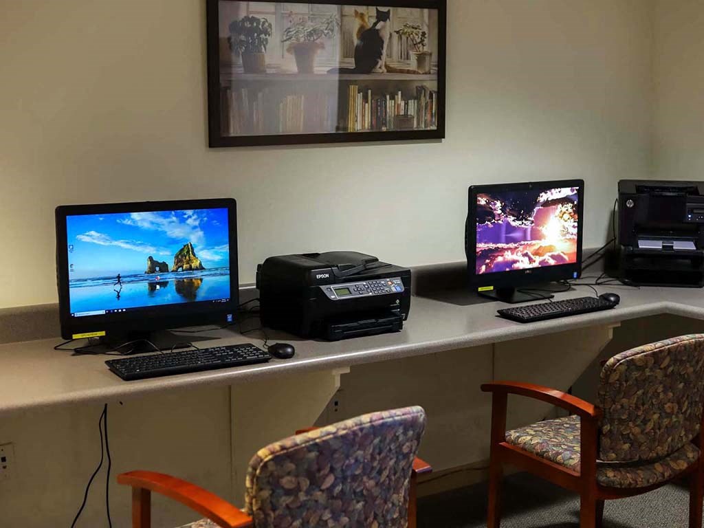 a desk with two computers and a printer on it