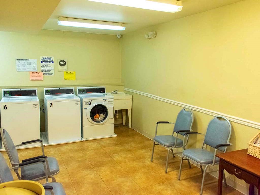 a laundry room with washing machines and chairs