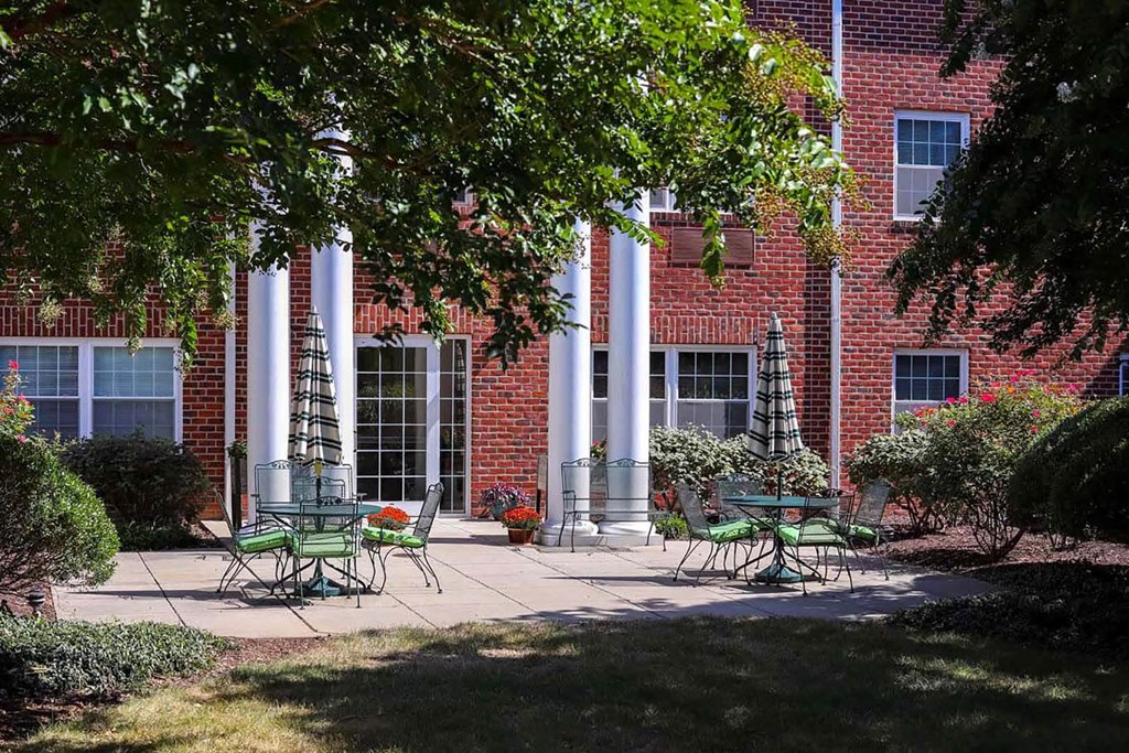 a patio with tables and chairs in front of a brick building