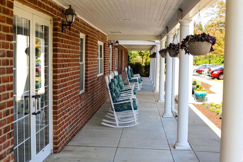 a row of rocking chairs on the porch of a brick building