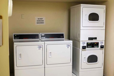 a row of washing machines and dryers in a laundry room