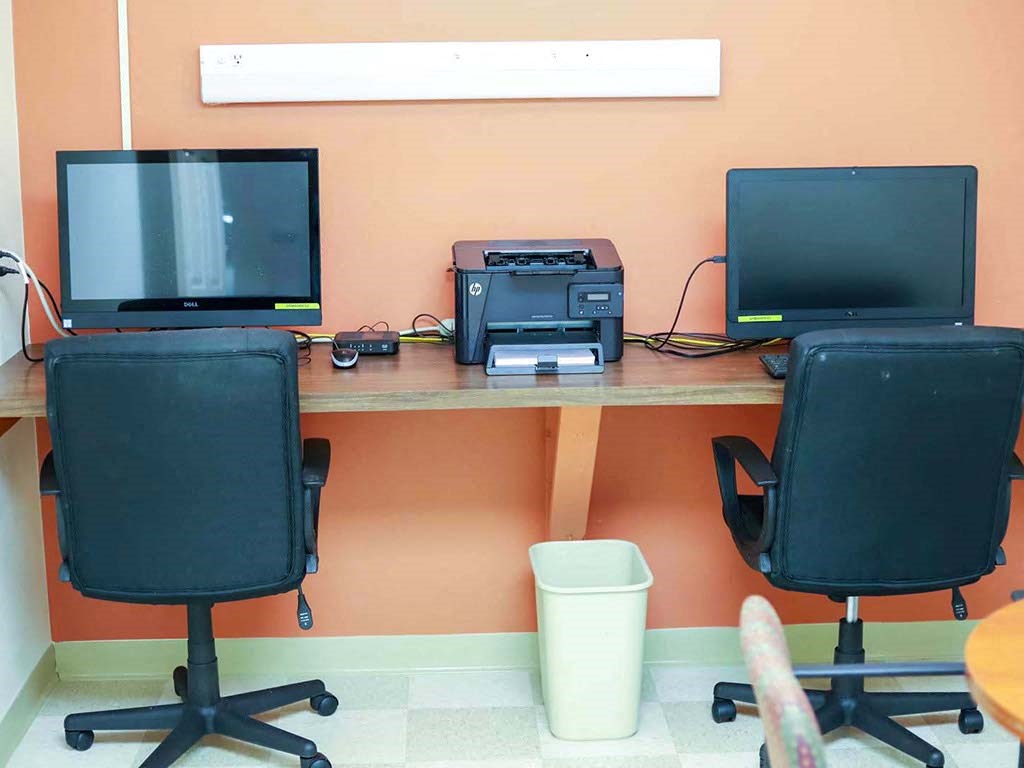 a desk with two computer monitors and a printer on it