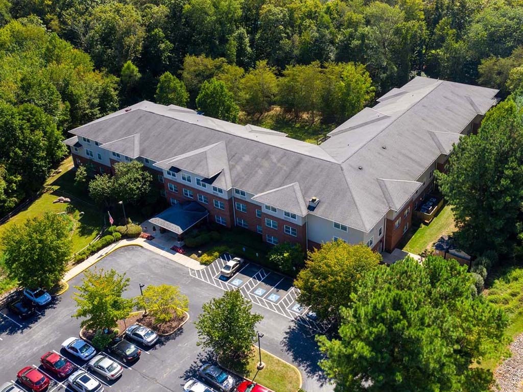 an aerial view of a building with parking lot and trees