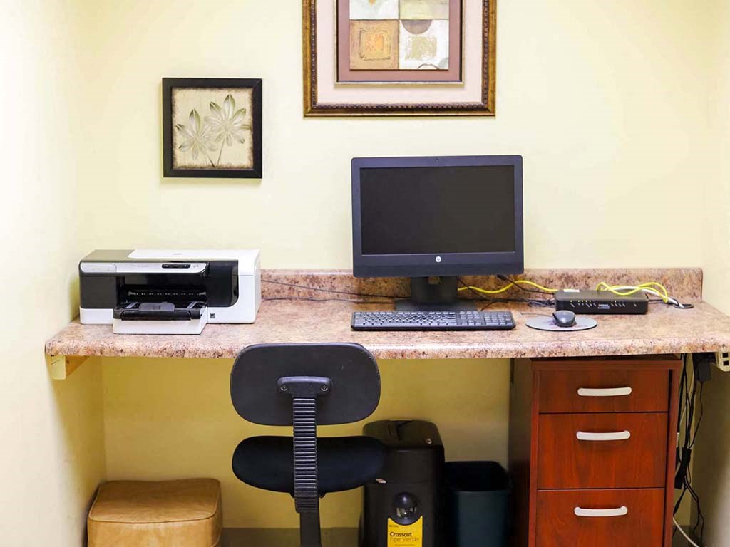 a desk with a computer and printer in a hotel room
