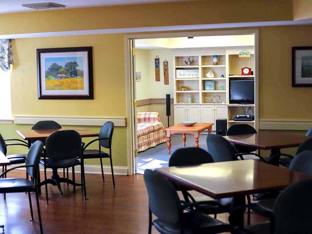 a dining room with tables and chairs and a living room with a couch