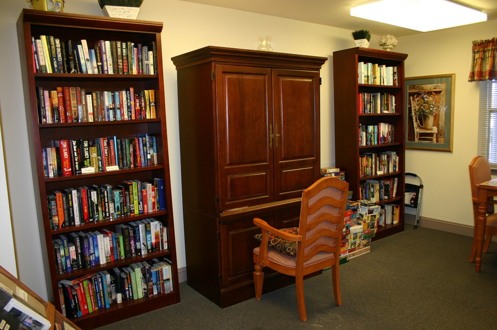 a library with three bookshelves and a chair and a cabinet