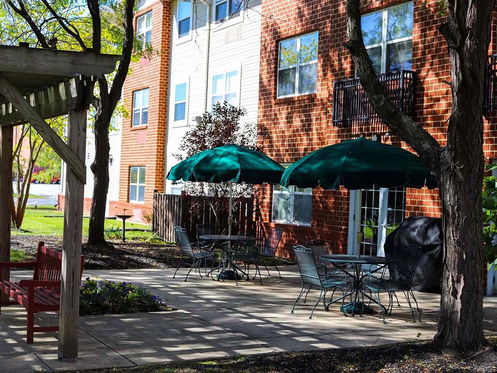 a patio with tables and umbrellas in front of a brick building