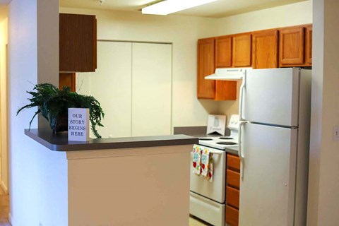 a kitchen with white appliances and a counter with a sign on it