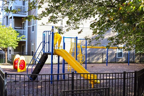 a playground with a yellow slide in front of a building