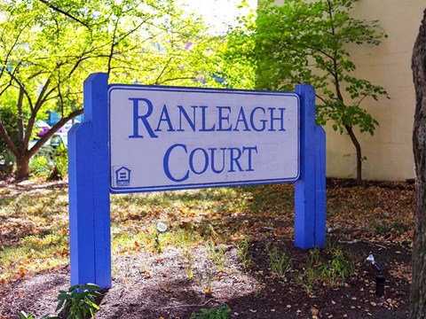 A blue sign that says Ranleigh Court stands in front of a tree.
