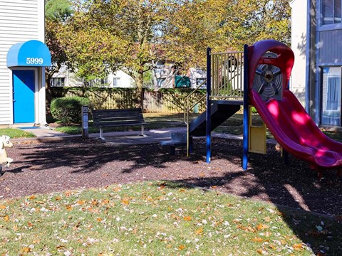 A playground with a red slide and a blue door with the number 5999 on it.