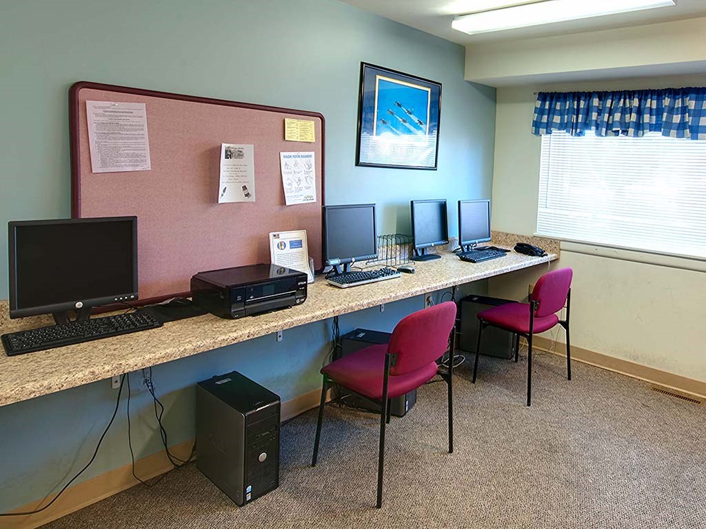 a long desk with computers and chairs in a room