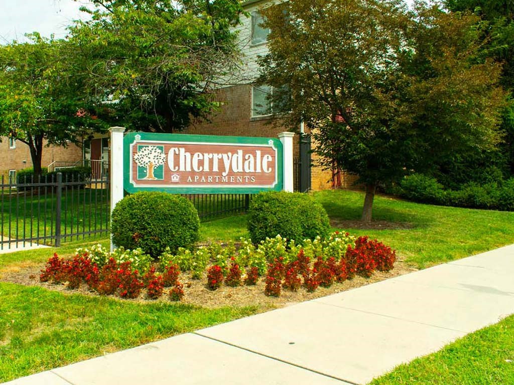 a sign and apartments in front of a garden