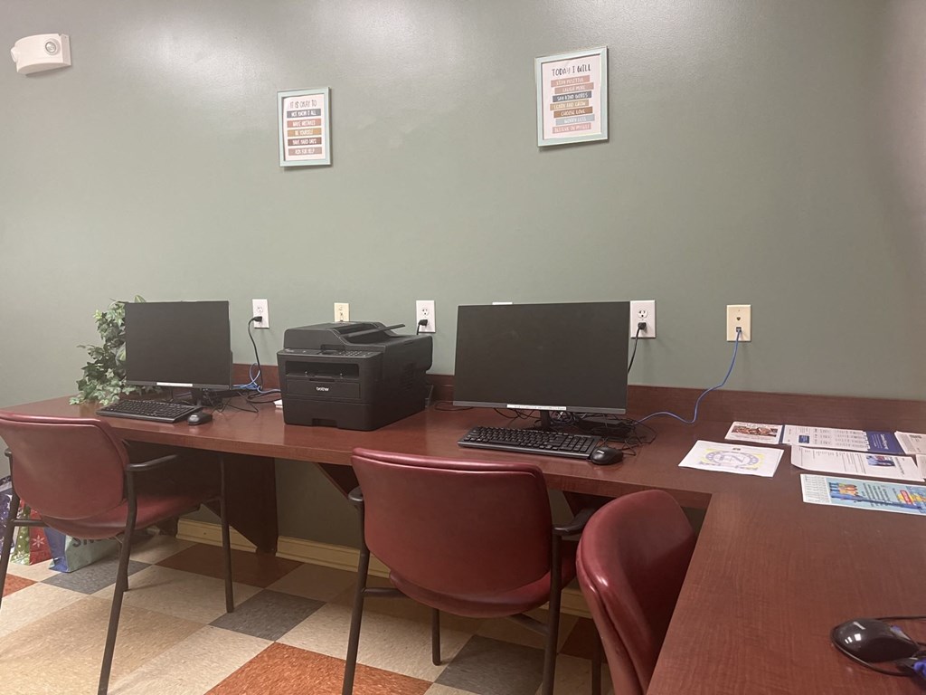 a desk with two computers and a printer on it