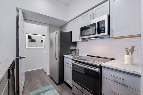A kitchen with a black fridge and stove top oven.
