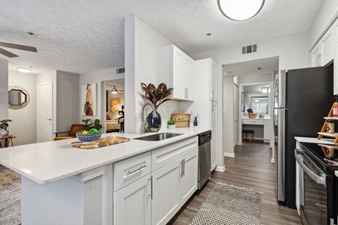 A kitchen with white cabinets and a black fridge.