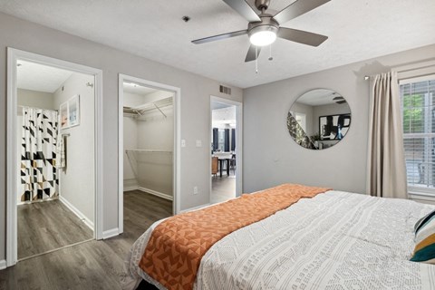 A bedroom with a bed, a ceiling fan, and a mirror on the wall.