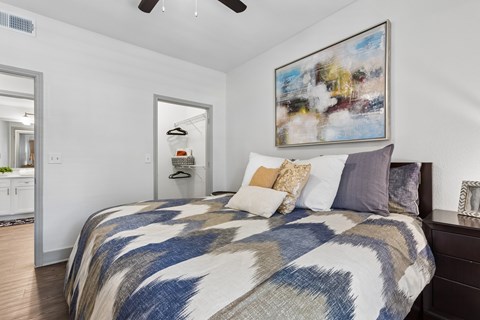 A bedroom with a large bed and a painting on the wall.