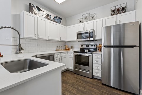 A kitchen with white cabinets and a stainless steel refrigerator.