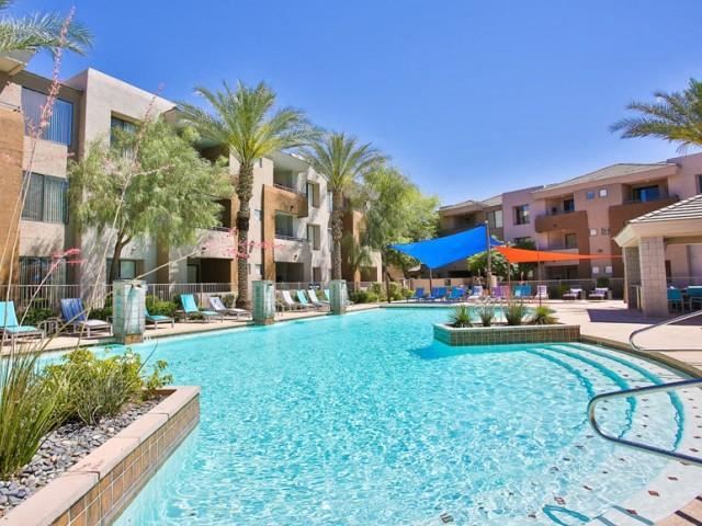a large swimming pool with palm trees and buildings