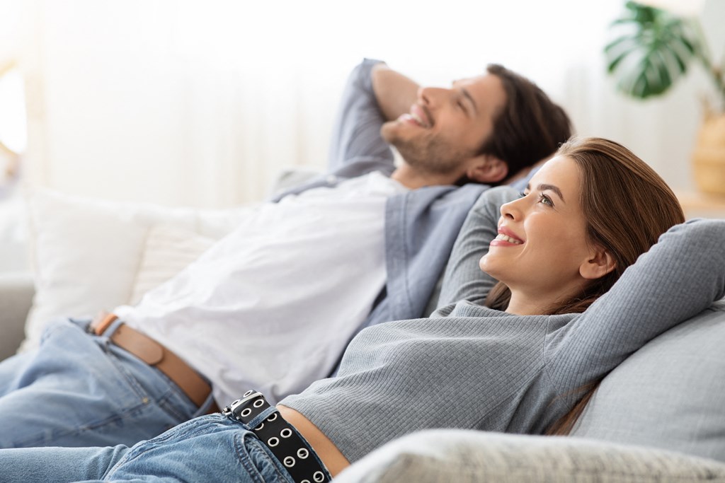 a man and a woman laying on a couch in the living room
