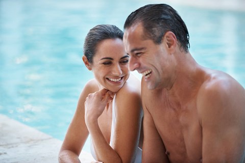 a man and woman sitting by a swimming pool