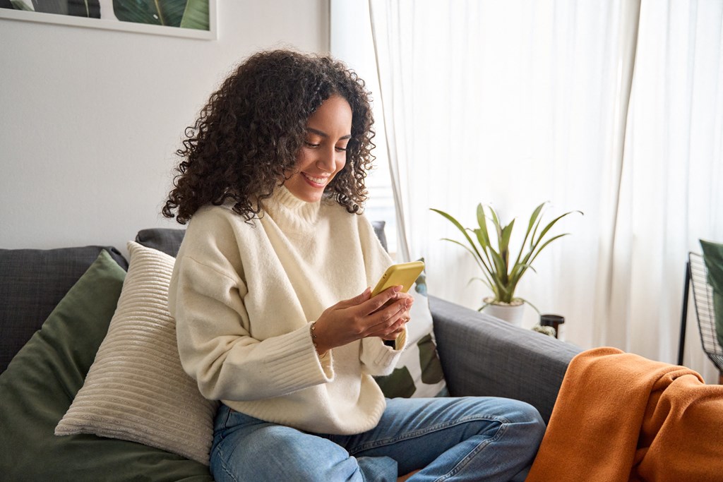 a woman sitting on a couch looking at her cell phone