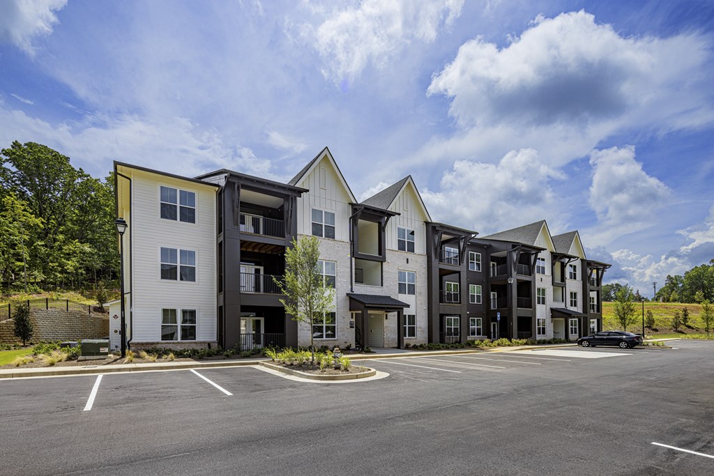 A row of modern townhouses with a parking lot in front at Folksong Apartments, Flowery Branch, 30542