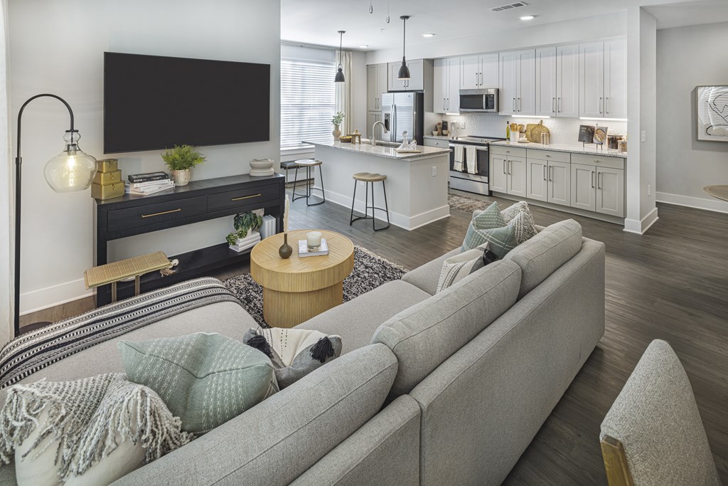 A modern living room with a grey sofa and a black TV at Folksong Apartments, Flowery Branch