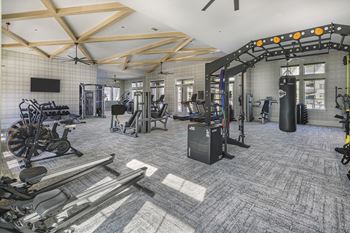 A gym with a variety of equipment including treadmills, weights, and exercise machines at Folksong Apartments, Flowery Branch, Georgia