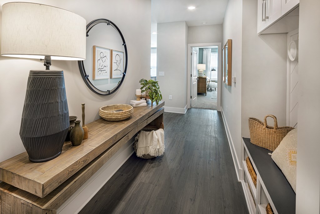 A hallway with a wooden floor and a round mirror on the wall at Folksong Apartments, Flowery Branch, GA 30542