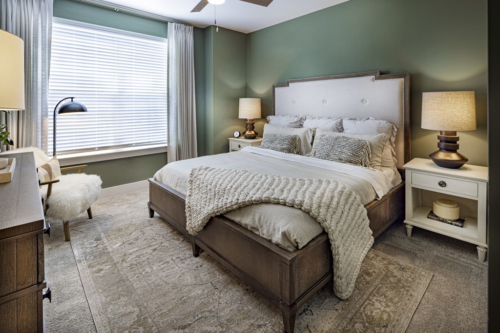 A bedroom with a large bed and a white chair at Folksong Apartments, Flowery Branch