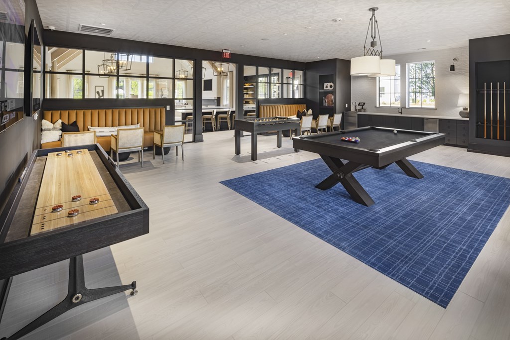 A pool table is in the middle of a room with a blue rug at Folksong Apartments, Georgia 30542