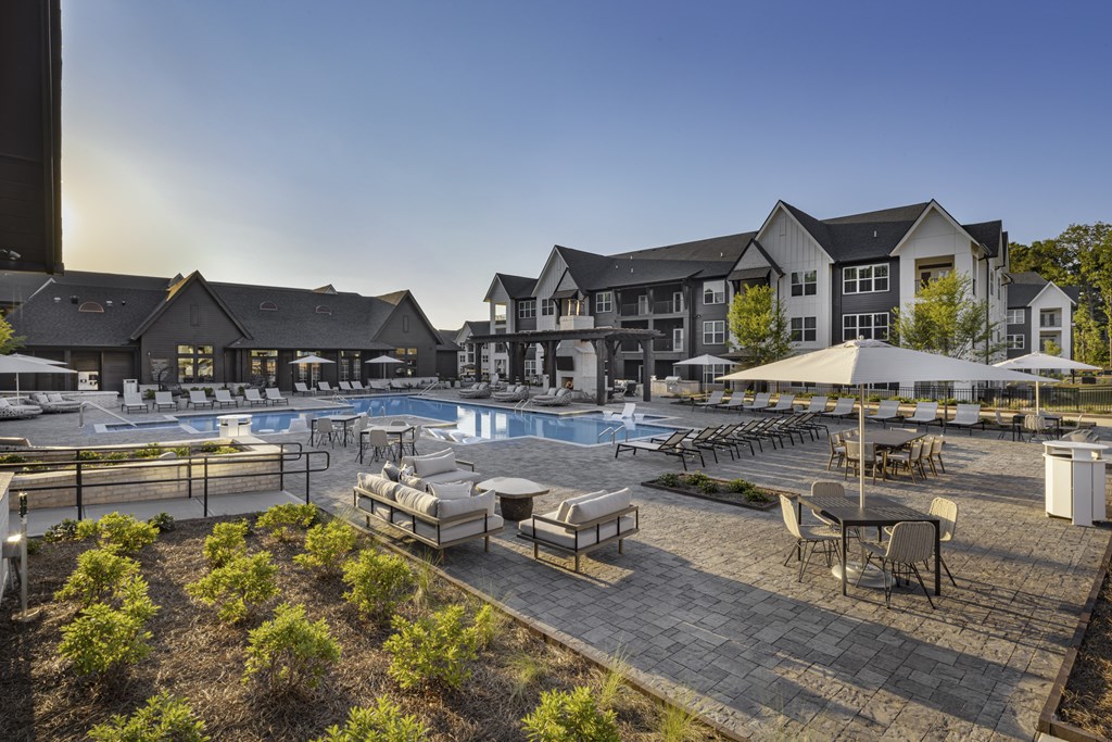 A large outdoor pool area with lounge chairs and umbrellas at Folksong Apartments, Flowery Branch, 30542