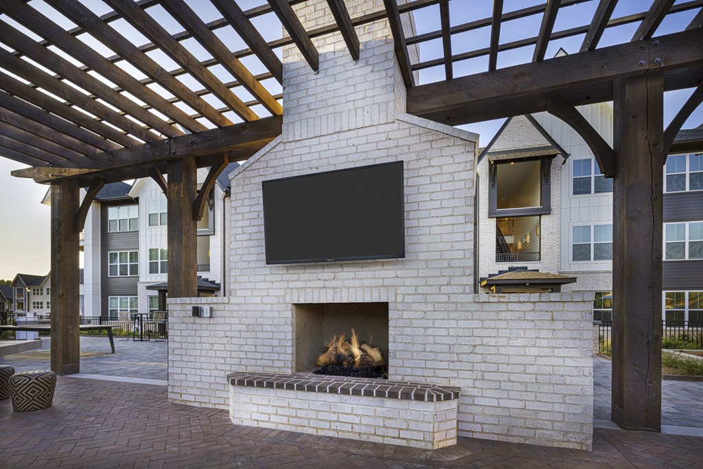 A fireplace with a TV above it is under a wooden pergola at Folksong Apartments, Flowery Branch, Georgia