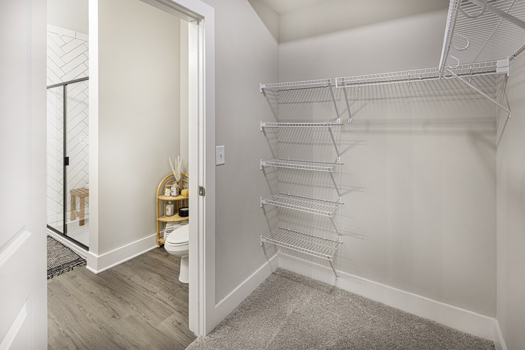 A white closet with shelves and a toilet visible through the open door at Folksong Apartments, Flowery Branch, GA