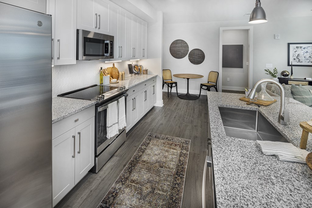 A modern kitchen with a refrigerator on the left and a dining area in the middle at Folksong Apartments, Flowery Branch, Georgia