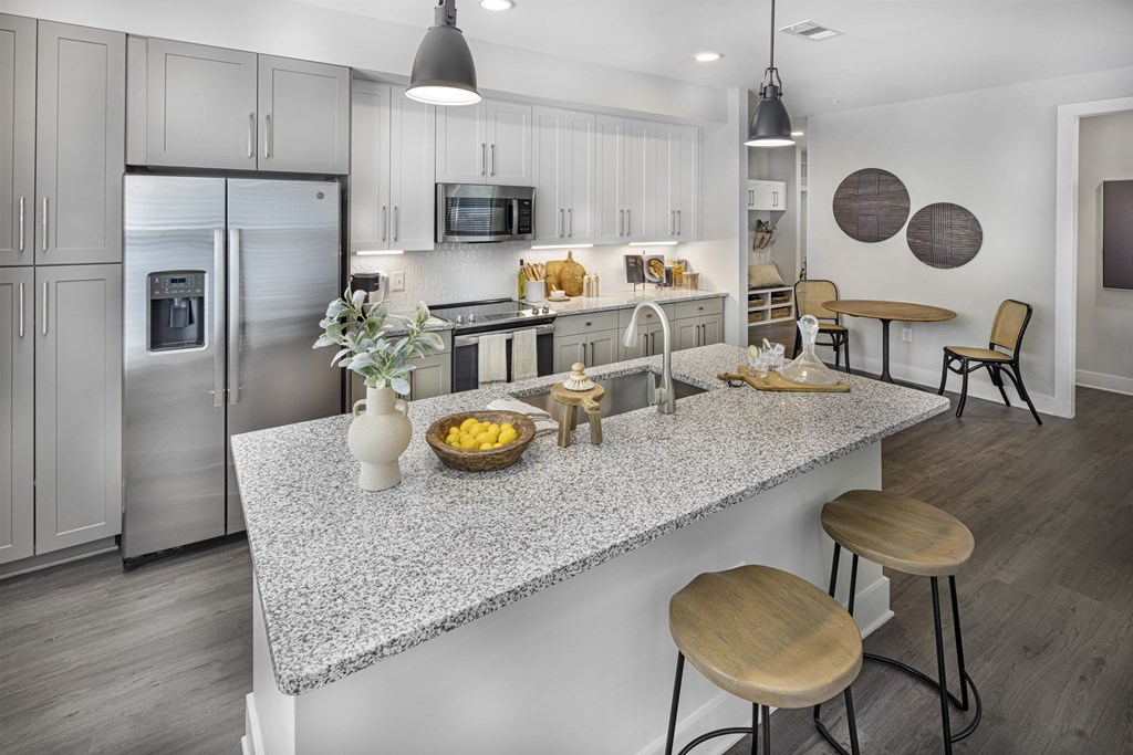 A modern kitchen with a granite countertop and stainless steel appliances at Folksong Apartments, Flowery Branch