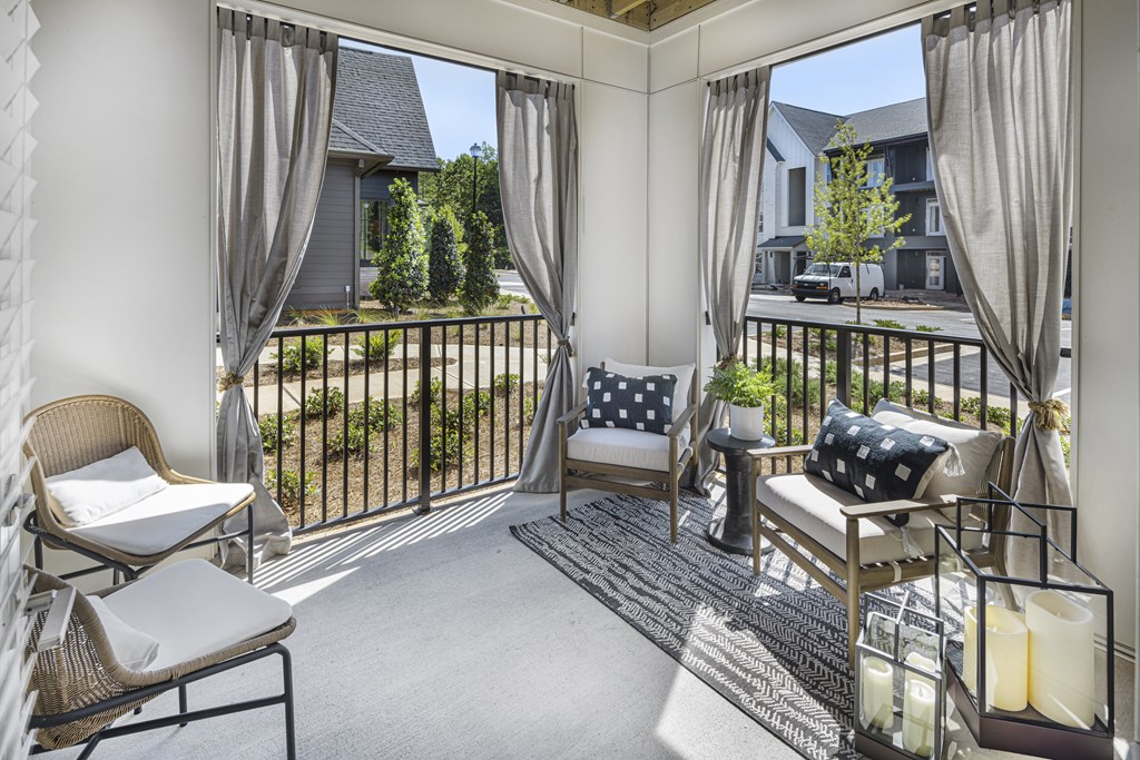 A sunny balcony with a chair, cushion and table at Folksong Apartments, Georgia
