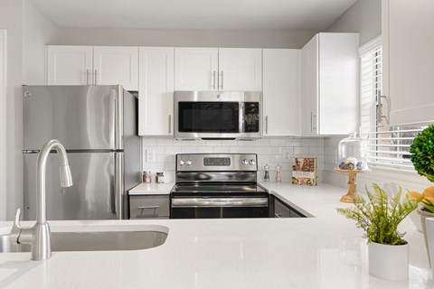 a white kitchen with stainless steel appliances and a sink