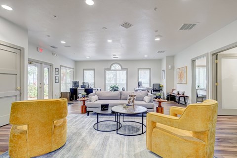 A spacious living room with a yellow chair and a grey couch.
