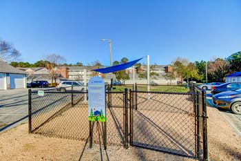 a gate with a sign on it in front of a parking lot with houses in the background
