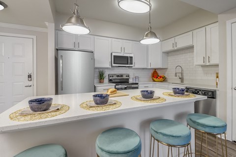 an open kitchen with a counter with blue stools and a counter top with bowls