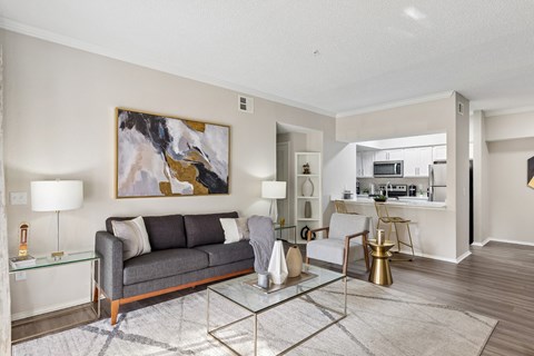 A modern living room with a grey sofa and a glass coffee table.