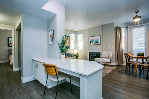 A kitchen with a white counter and orange chairs.