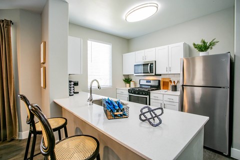 A kitchen with a white countertop and a stainless steel refrigerator.