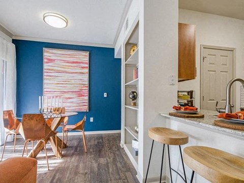 A kitchen with a blue wall and a dining table with chairs.