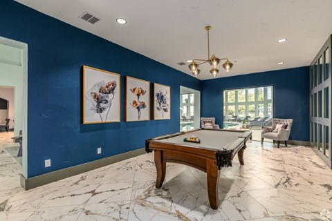 A pool table in a room with blue walls and marble flooring.