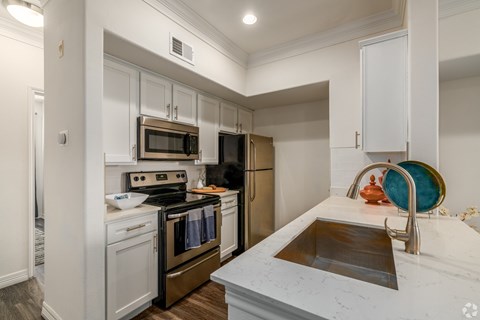 A kitchen with white cabinets and a marble countertop.
