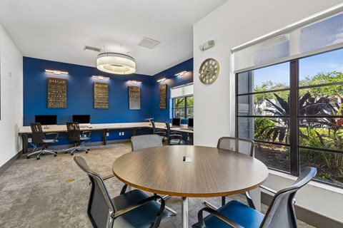 A conference room with a table, chairs, and a view of the outdoors.